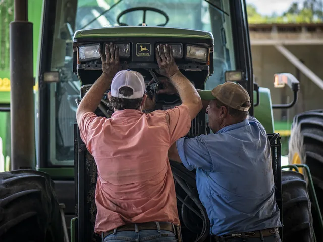 Szakember traktor motorját vizsgálja a javítóműhelyben
